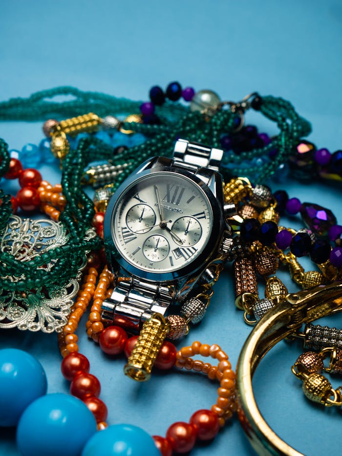 Contact Close-up of elegant wristwatch surrounded by colorful beaded bracelets, showcasing vibrant fashion accessories.