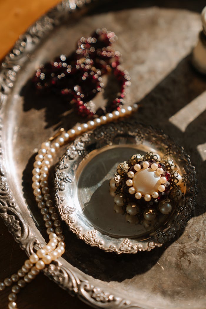 Capture of a vintage silver tray adorned with pearls and intricate brooch, exuding elegance and classic style.